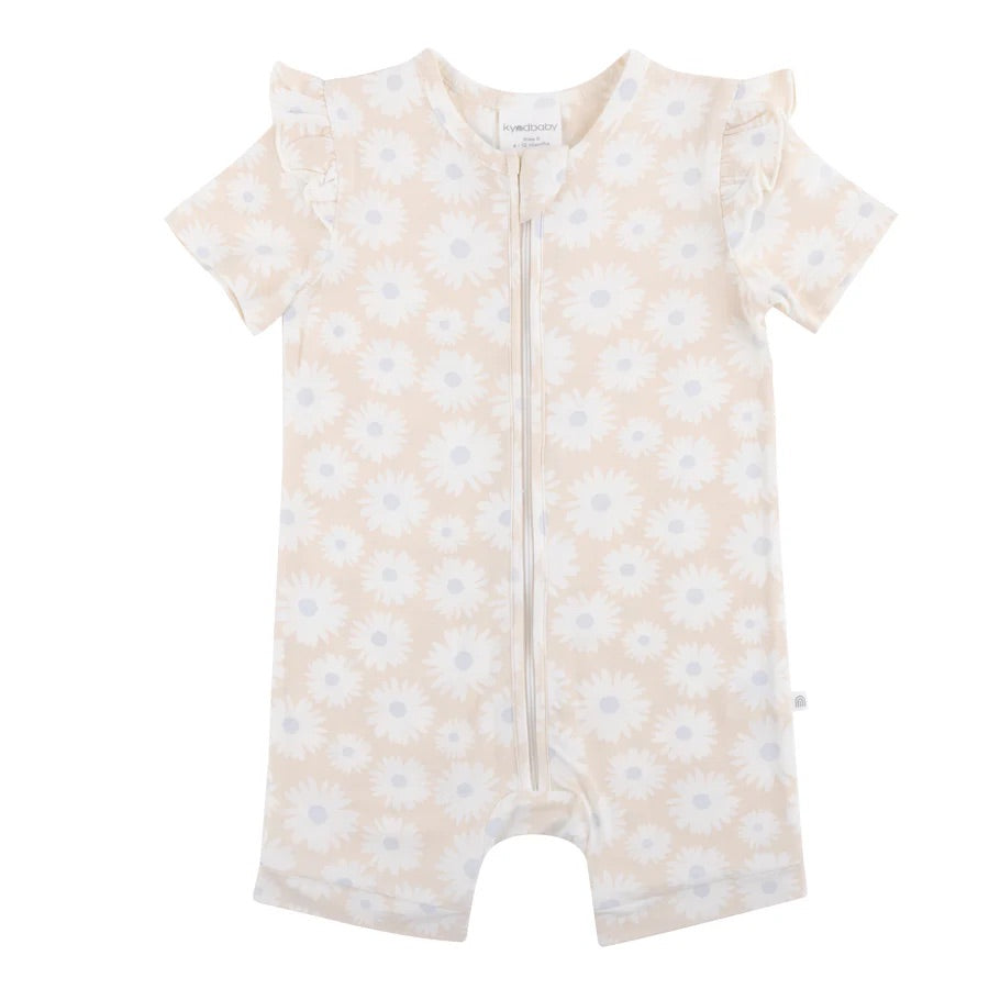 The KYND BABY Day or Night Short Sleeve Frill Onesie Petal Fields is crafted from EcoCosy Viscose, designed for summer with short sleeves and ruffled shoulders. It has a charming white daisy pattern and a front zipper, making it a perfect sustainable choice for your little one's wardrobe.