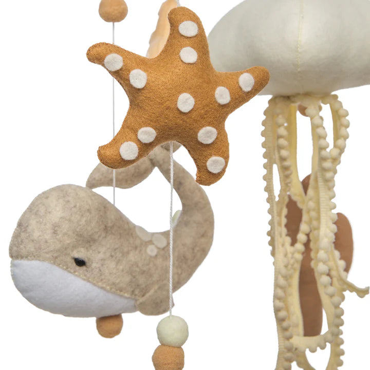 The ROOMI & ME "Roomi & Me - Baby Mobile Underwater Dreaming" showcases a beige whale, orange starfish with white spots, and cream jellyfish tentacles, all hanging from strings with felt beads for gentle visual stimulation.