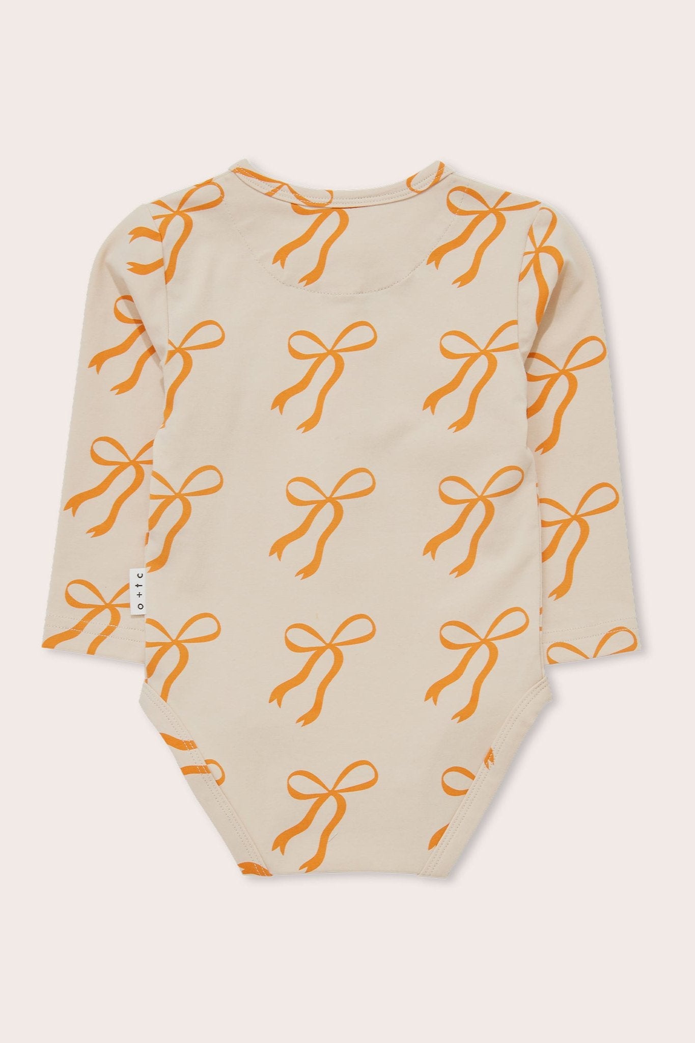 The Cream Bows Long Sleeve Bodysuit from OLIVE + THE CAPTAIN is a long-sleeved beige baby bodysuit adorned with an all-over print of golden bows. Crafted from soft stretch cotton terry, it features a round neckline and the brand's tag on the side seam.