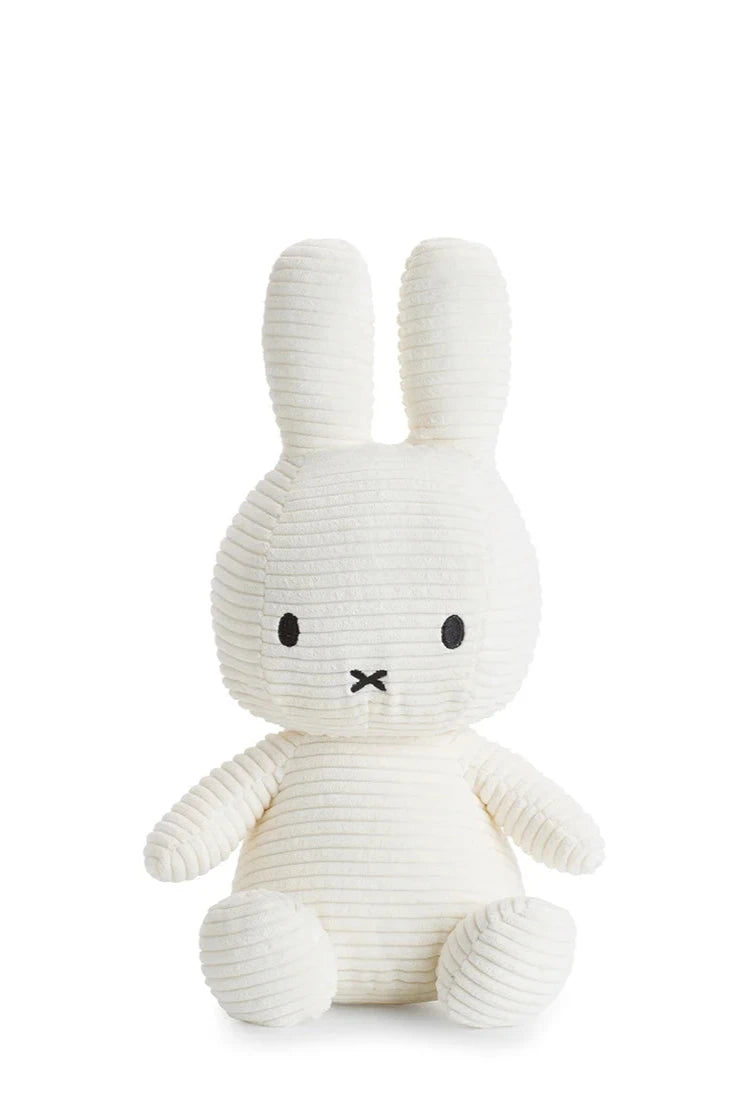 The Miffy ECO Corduroy Off White 33 cm from BON TON TOYS X MIFFY is a plush toy crafted in the likeness of a white rabbit with long ears and a small black embroidered face, featuring a ribbed texture and filled with recycled PET. It sits upright against a plain white background, making it the perfect plush gift.