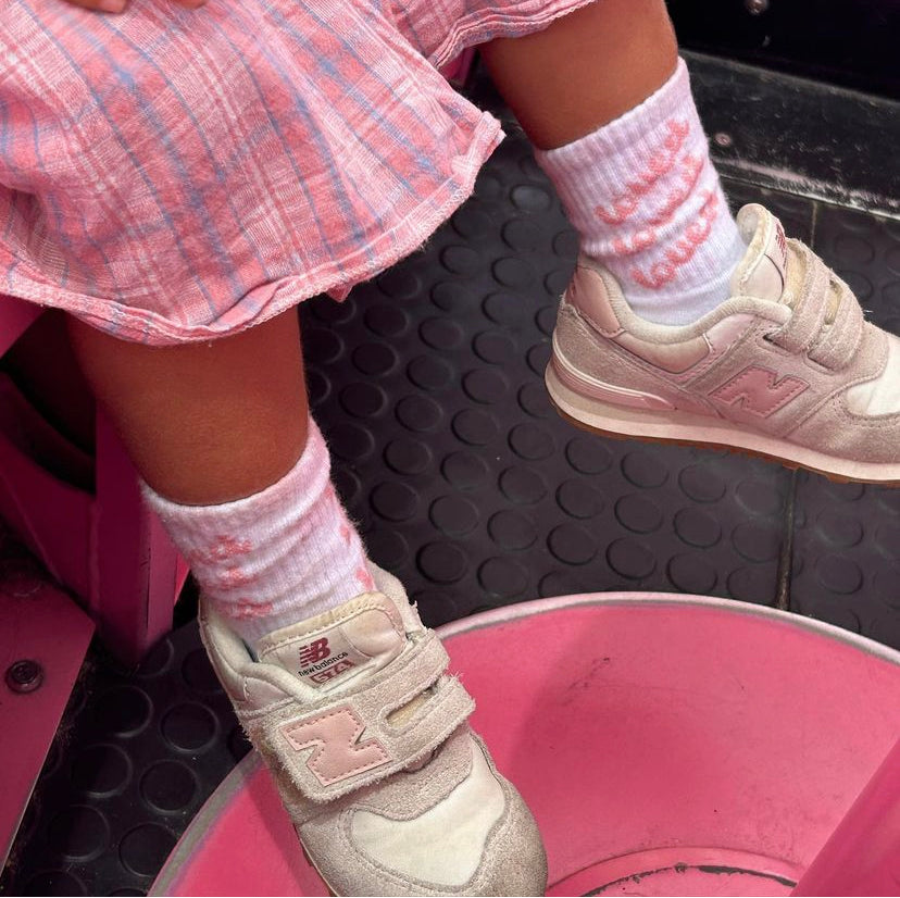 A young girl wearing the another love sick with white and pink sneakers and a pink skirt.