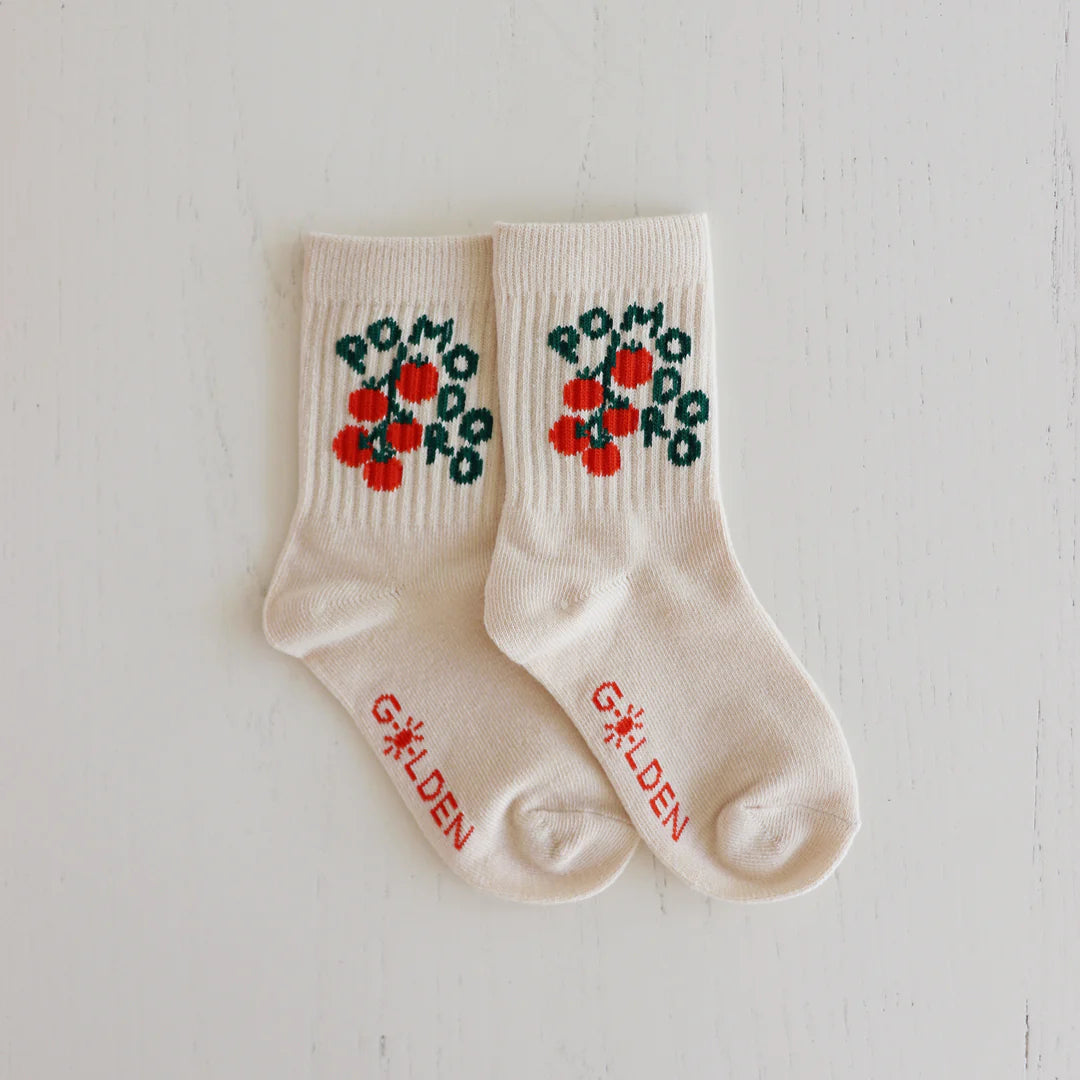 Golden Children - Pomodoro Socks Dough by GOLDEN CHILDREN: Cream socks with red tomato and green leaf designs, "POMODORO" in green, "GOLDEN" in red near the toes, reinforced toe caps, inspired by homegrown pomodoro style.