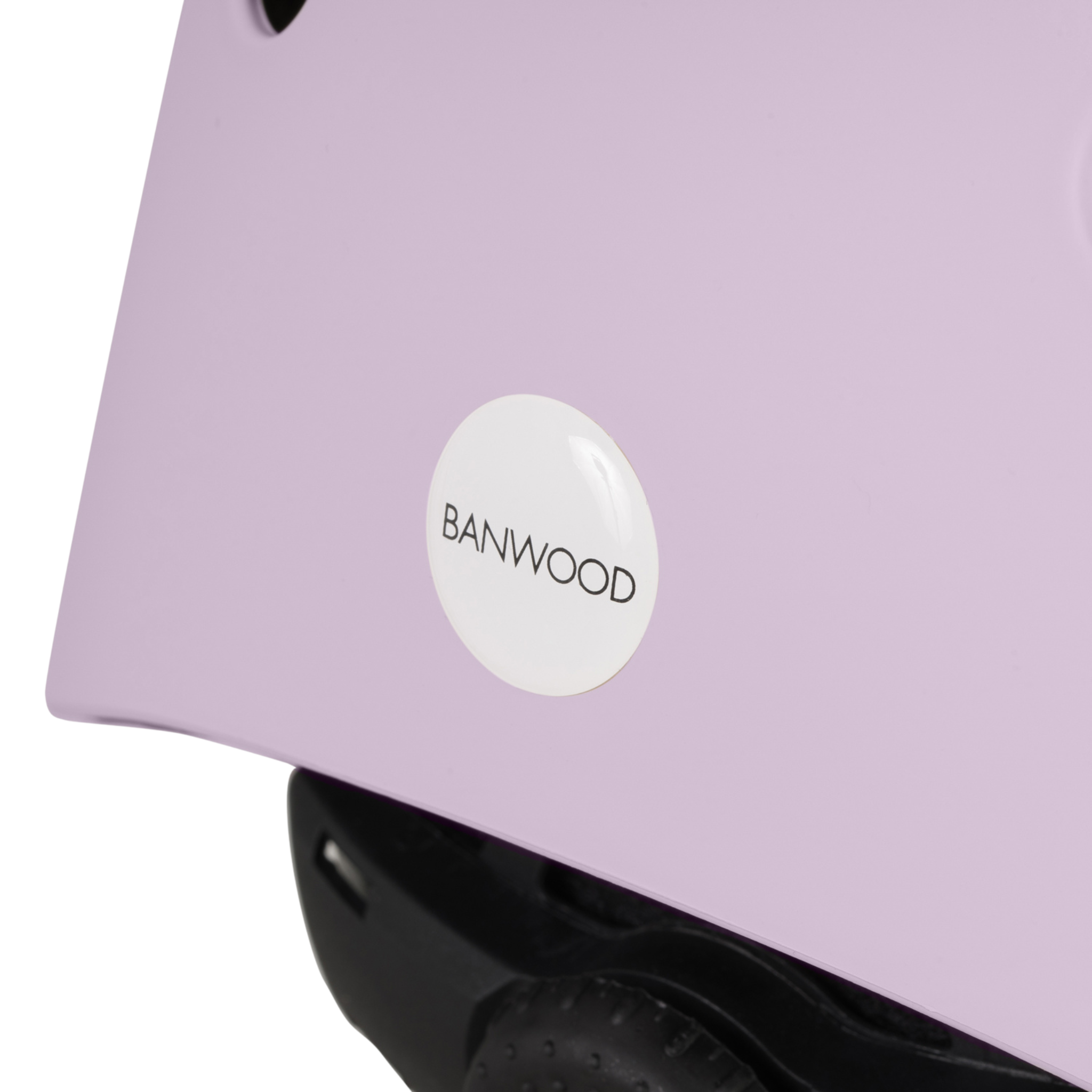 A close-up of the Banwood Eco Helmet Lavender reveals its lavender hue, crafted from recycled materials. The BANWOOD logo is visible on the side, with glimpses of the edge and adjustment mechanism highlighting its safe and sustainable design.