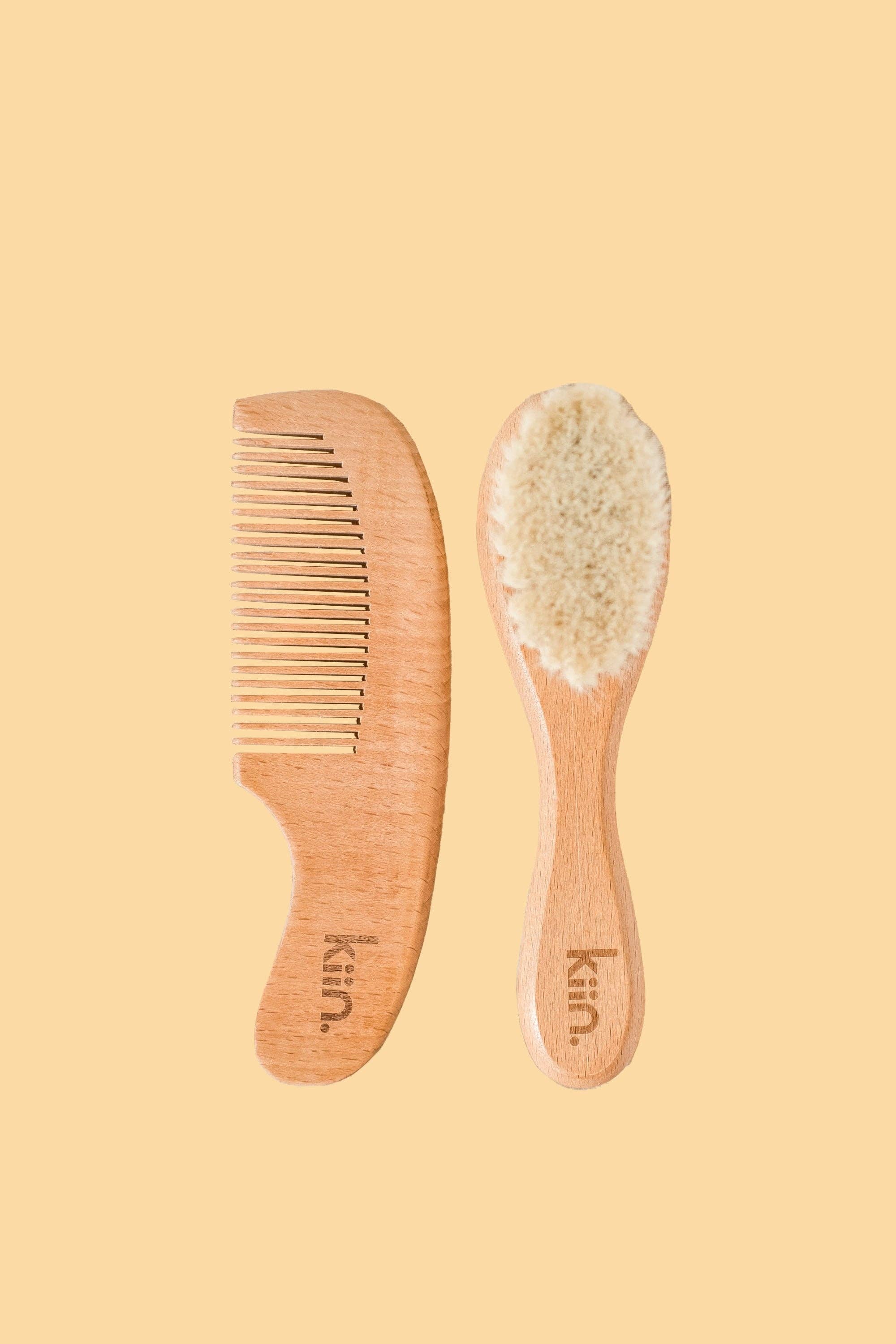 The KIIN BABY Wooden Baby Brush and Comb Set features a fine-toothed wooden comb and a soft-bristled brush made from eco-friendly materials with light-colored wood and gentle goat wool, displayed on a beige background.