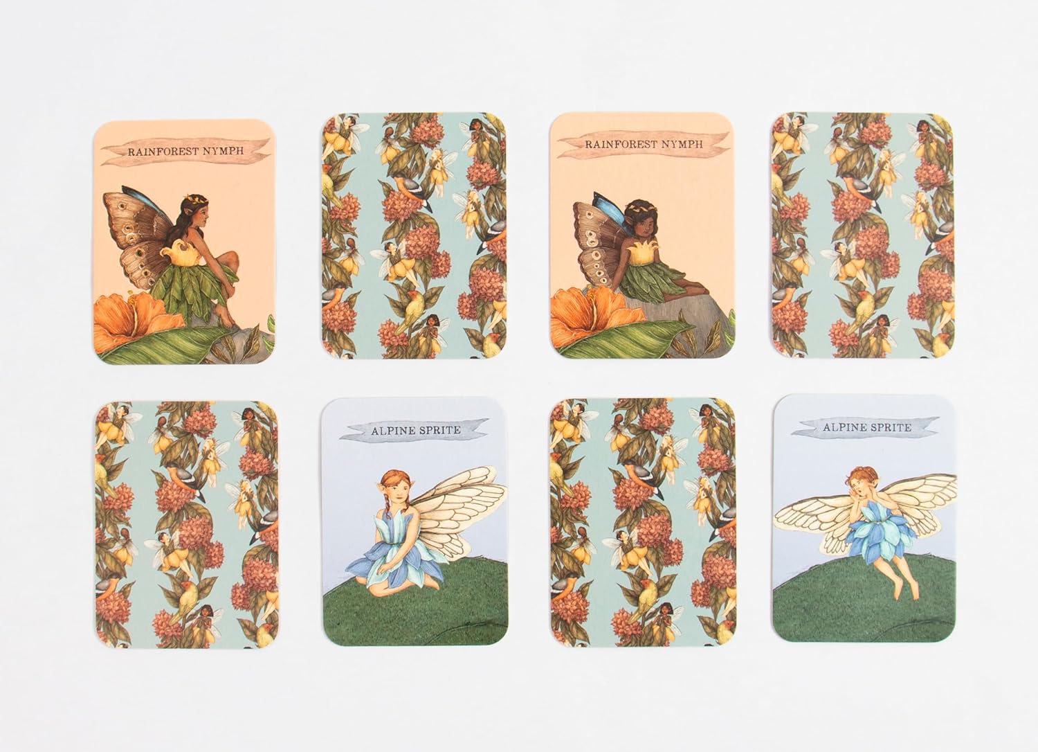 Eight matching cards from BAY KIDS' Find the Fairies: A Memory Game are shown in two rows—four feature “Rainforest Nymph” and “Alpine Sprite” fairies on flowers or grass, while four display coordinating floral patterns.