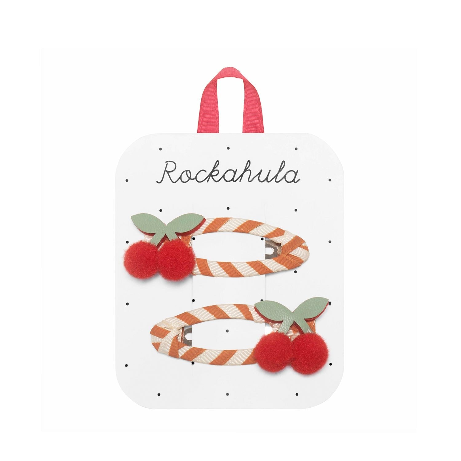 Two striped cherry hair clips with red pom-pom cherries and green recycled felt leaves, from ROCKAHULA's "Sweet Cherry Clips," displayed on a white "Rockahula" card with a pink grosgrain ribbon.