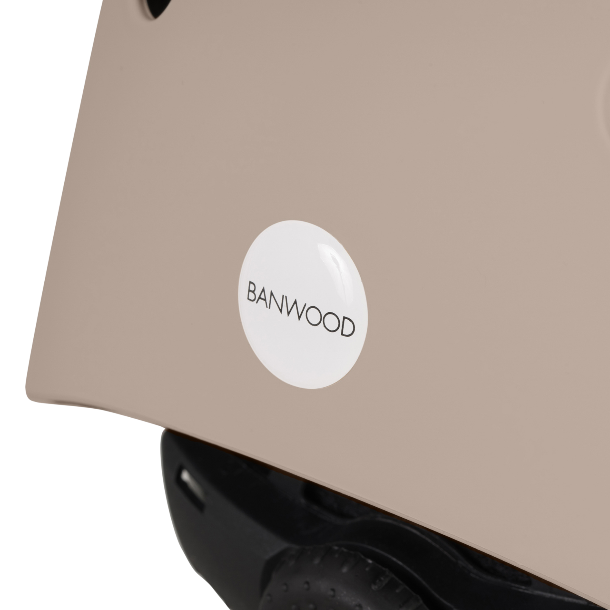 Close-up of Banwood's Eco Helmet Sand, made from recycled materials, with a black strap and a white circular "BANWOOD" logo, highlighting safety and sustainability.
