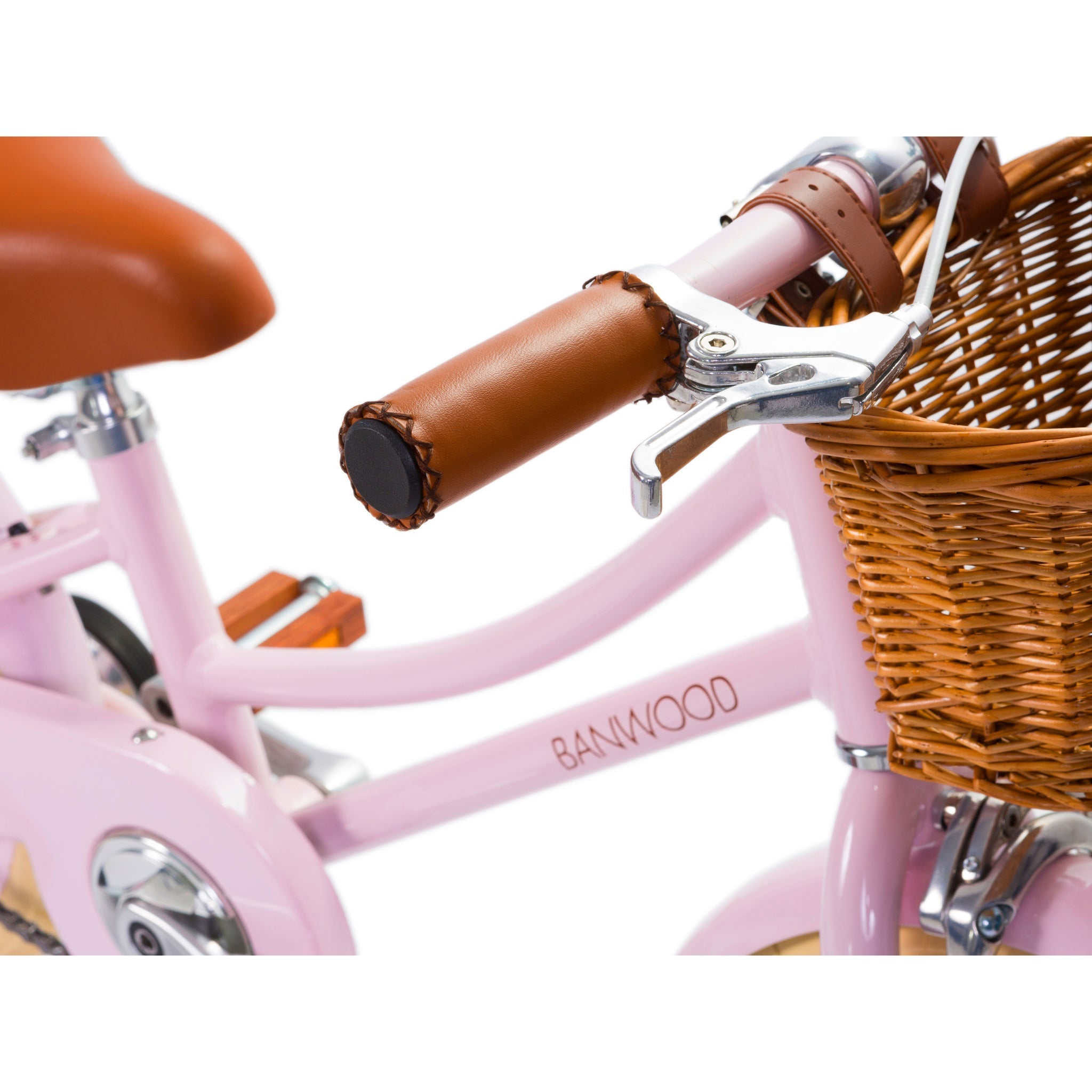 A close-up of the Banwood - Classic Bicycle Pink reveals its vintage-inspired design with a woven basket, brown leather grips, and a matching seat. The BANWOOD logo graces the frame, showcasing its Scandinavian design influence.