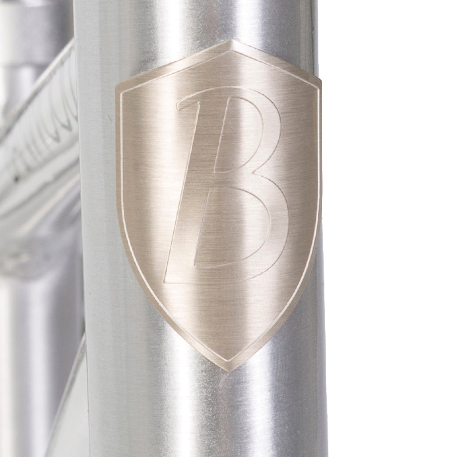 The Banwood - Vintage Balance Bike Chrome features a metallic frame with an embossed shield logo "B," showcasing a shiny, polished finish perfect for toddler cycling adventures.