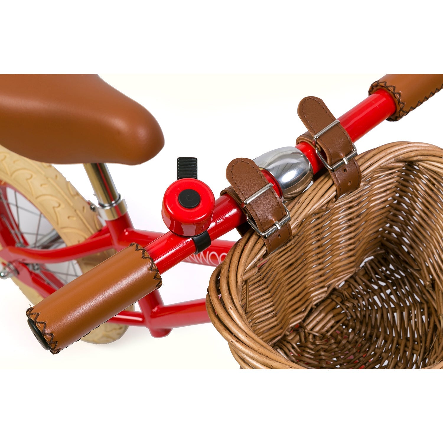 The Banwood - Vintage Balance Bike Red from BANWOOD features brown leather grips with a bell, a woven basket at the front, a brown seat, and matching handlebar straps, all exuding classic charm.