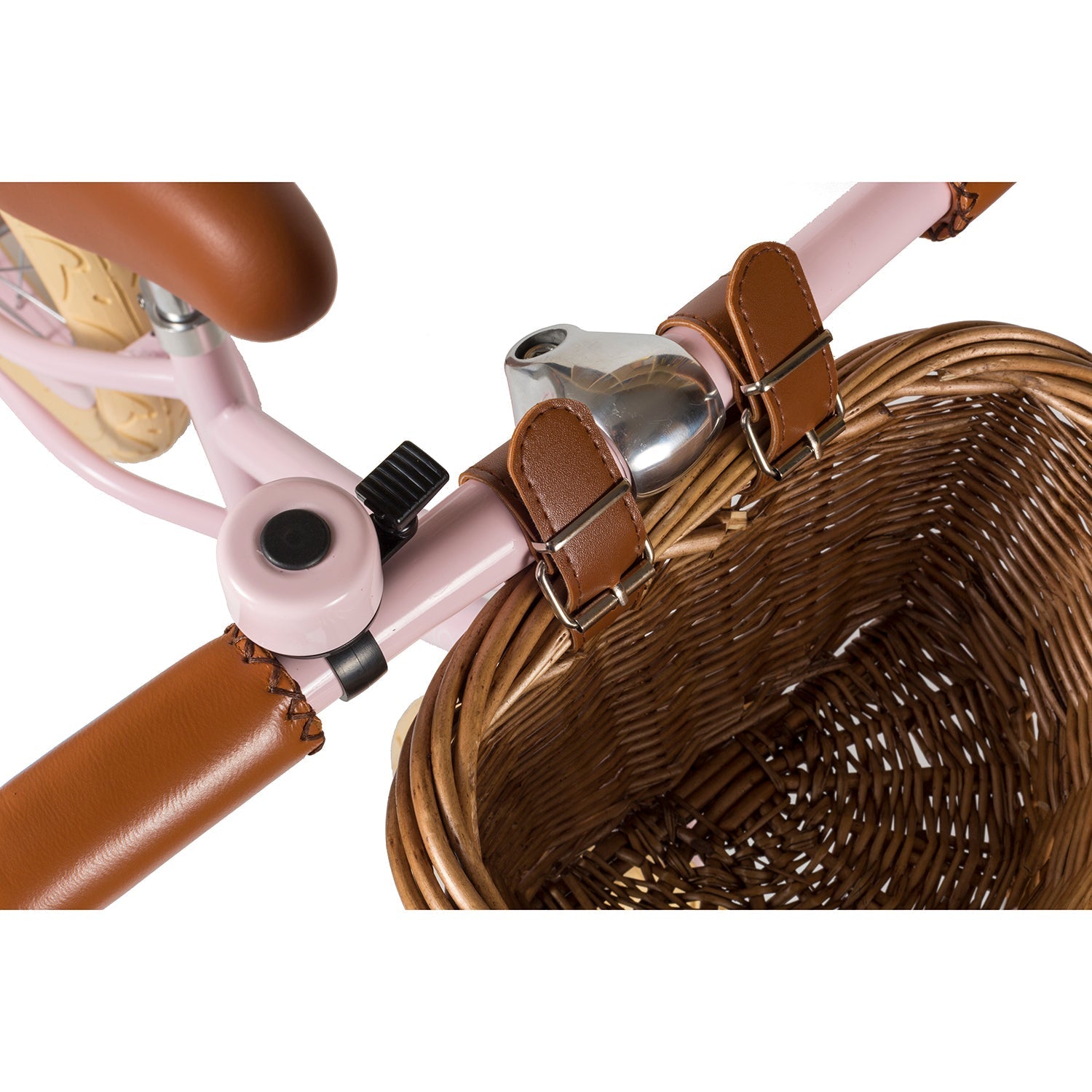 A close-up of the BANWOOD "Banwood - Vintage Balance Bike Pink" shows its vintage-styled handlebar with brown leather grips, a metal bell, and a wicker basket attached with leather straps—a pink frame enhancing its nostalgic charm.