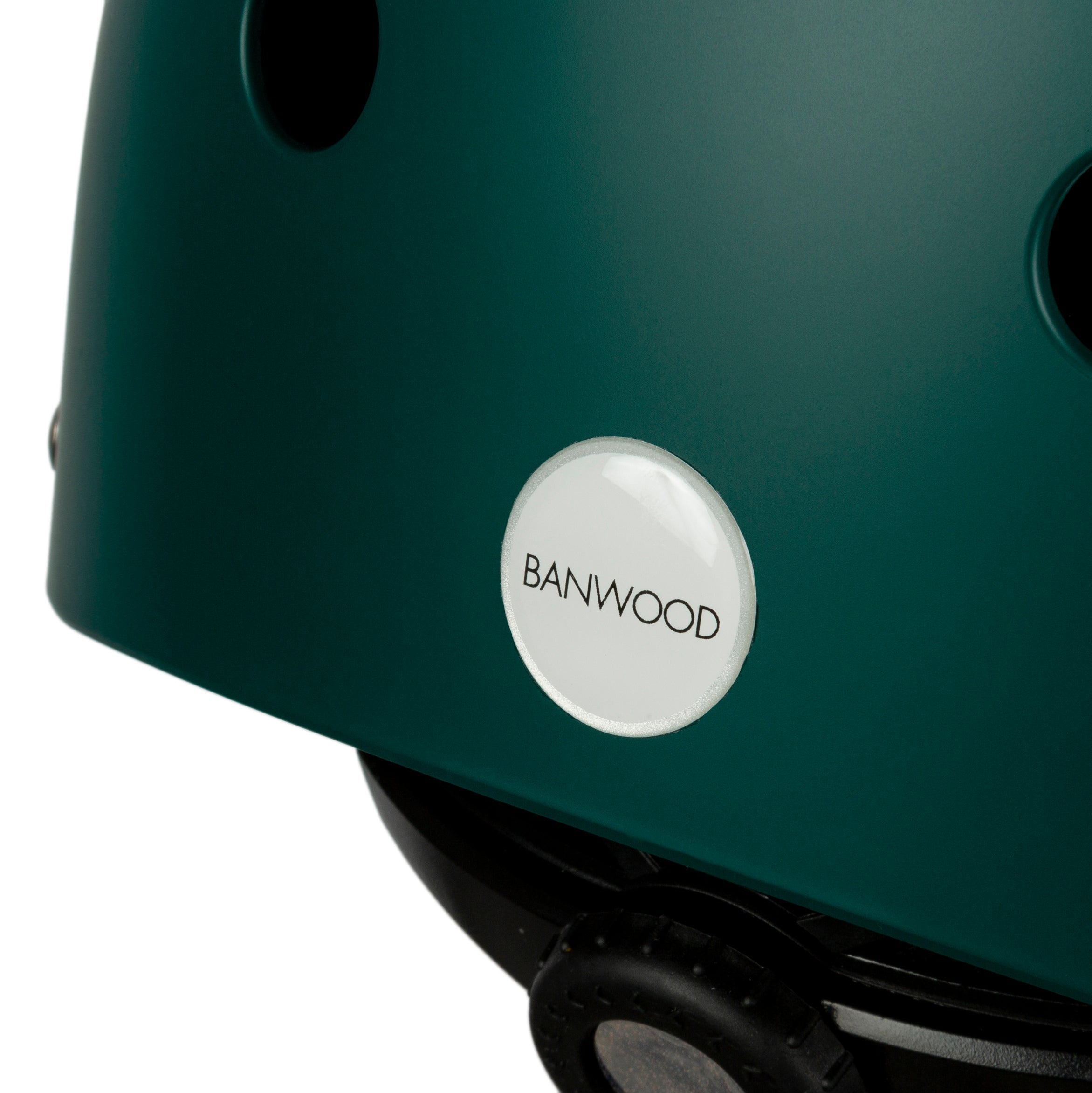Close-up of a dark green Banwood - Classic Helmet XS featuring ventilation holes, a visible white circular BANWOOD logo, and an adjustable strap for a secure fit, ensuring children's bike helmet protection.