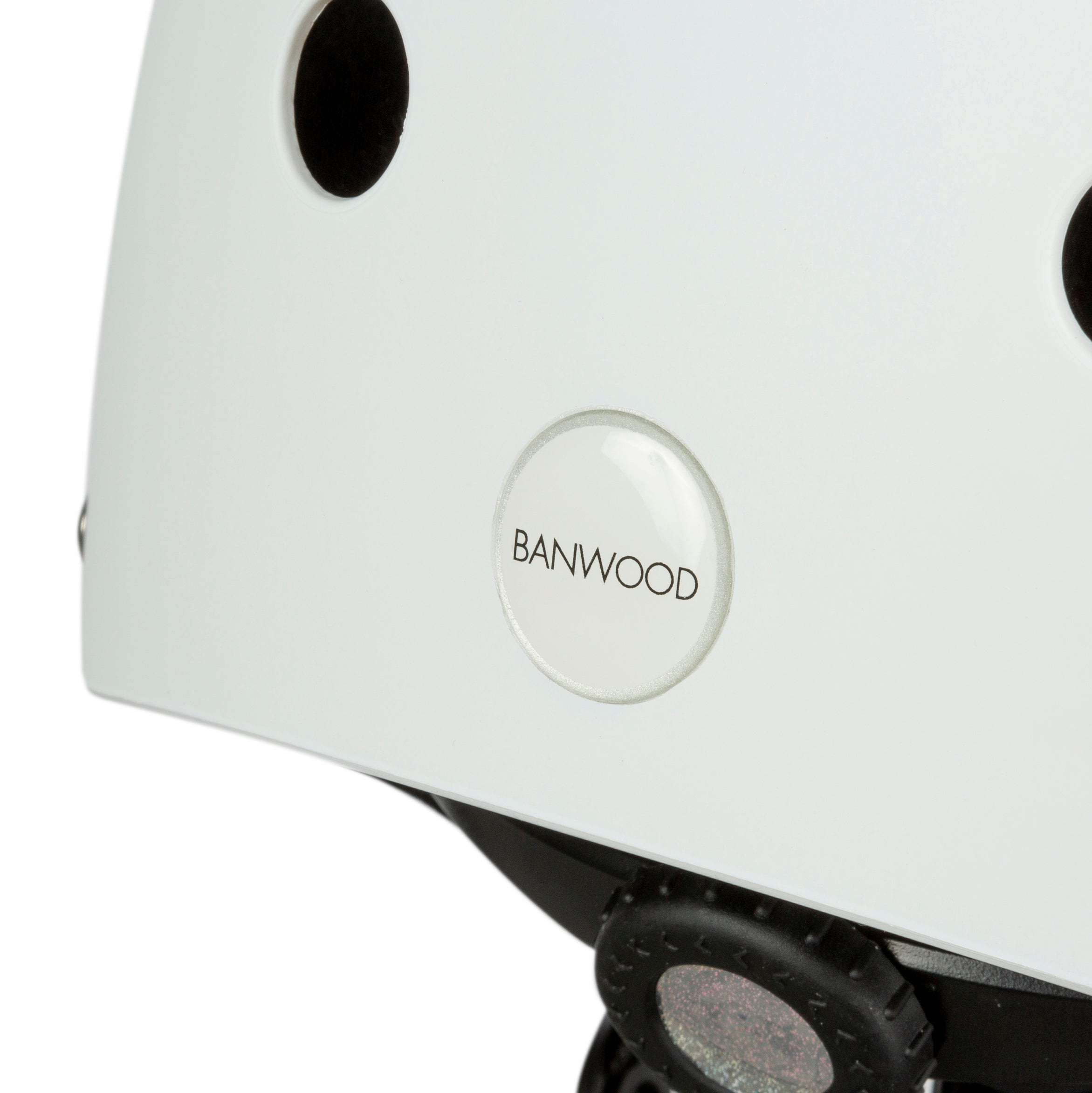 Close-up of BANWOOD's Classic Helmet White (XS) showcases the brand logo. Made from durable ABS, it features round ventilation holes and an adjustable black chin strap with a buckle.