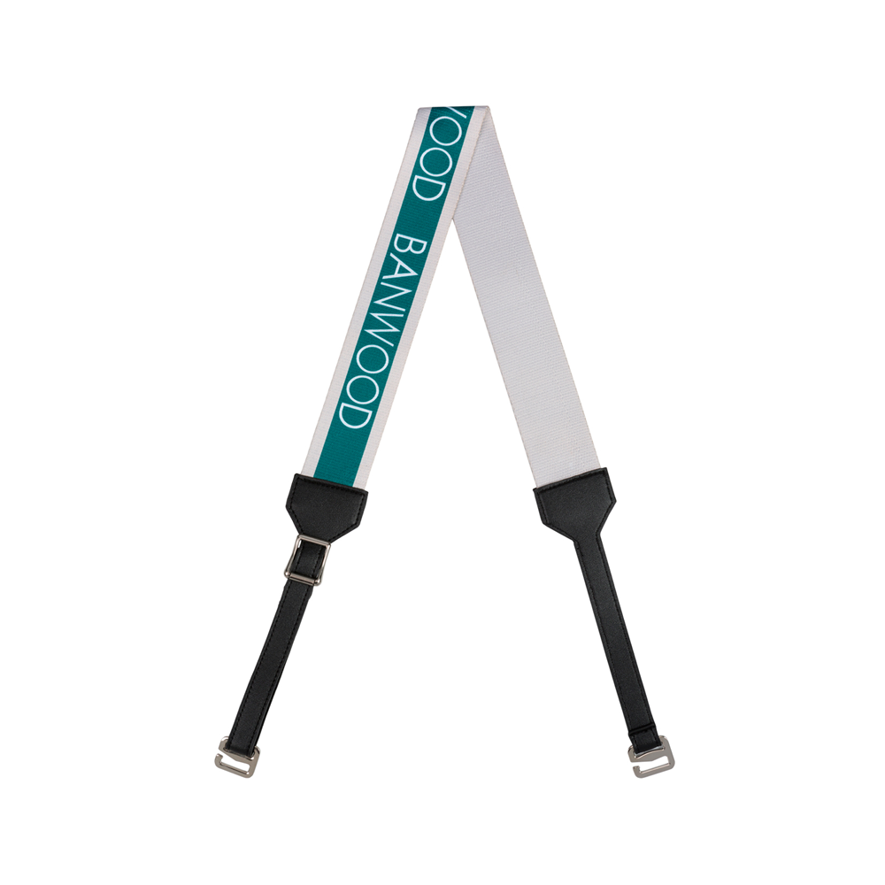 The Banwood Carry Strap Green, ideal for balance bikes or scooters, boasts a white and green look with "GOOD BANWOOD" in green lettering. It includes black leather ends and metal clips for secure fastening.