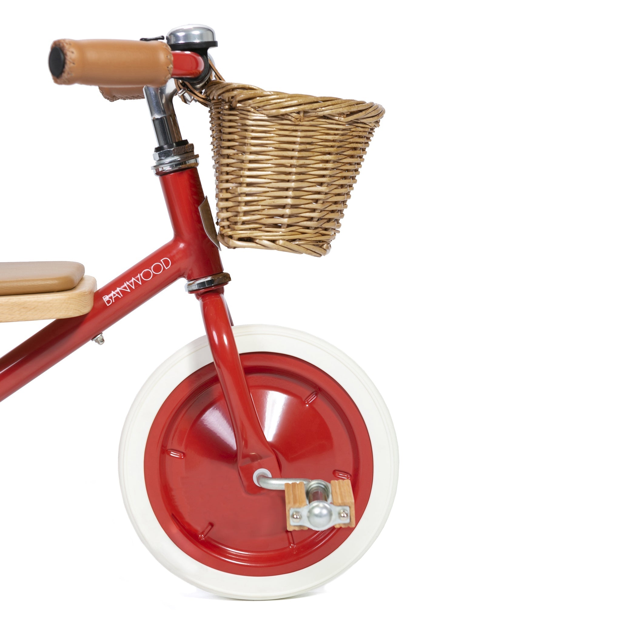 The Banwood - Trike Red is ideal for little adventurers, featuring a vibrant red frame with "BANWOOD" in white lettering. It includes a wicker basket, white tires, brown leather handlebar grips, and a wooden seat that stands out beautifully against the plain white background.
