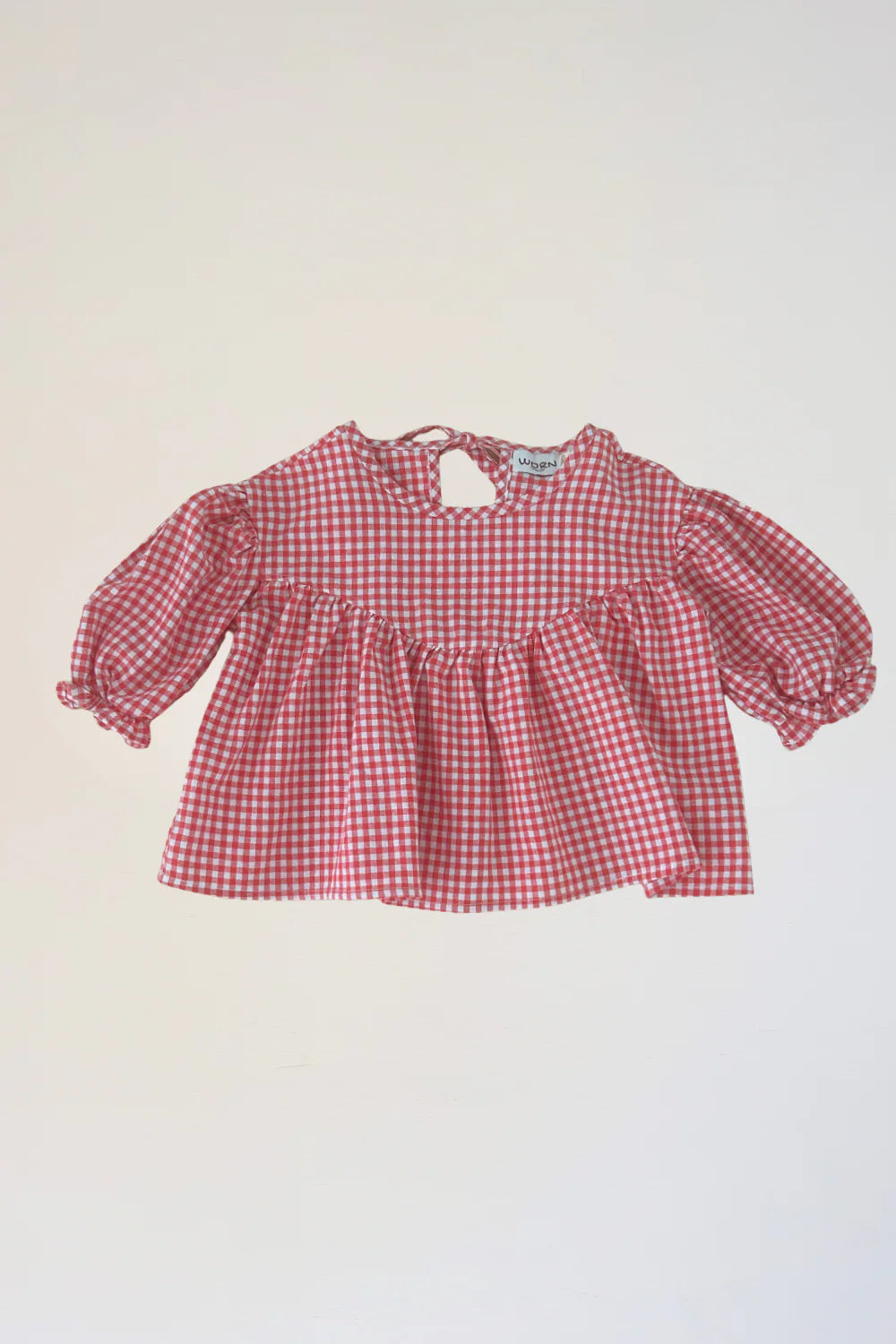 The WORN CURATIONS Gingham Bloom Blouse Chilli features red and white gingham, puffy cotton sleeves, a gathered waist, and a keyhole button back, shown on a plain white background.