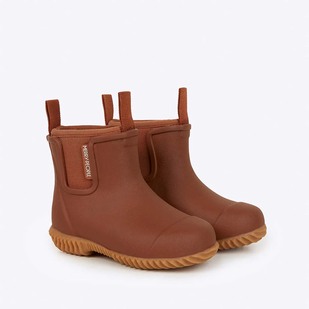 The MERRY PEOPLE Merry People - Bobbi Kids Gumboot Rust are vegan brown rubber ankle rain boots with pull tabs and textured tan soles, shown against a light gray background.