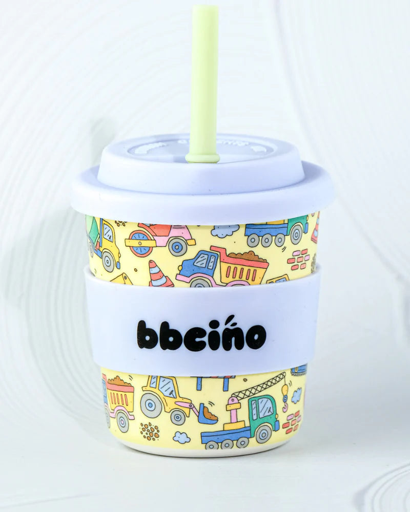 The BBcino Reusable BambinoCino Cup 240ml Dig It by BBCINO features a light purple lid and straw, colorful construction vehicles, a white "bbceíno" grip band, and is made from sustainably farmed bamboo for an eco-friendly choice.