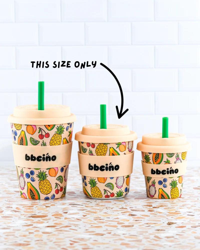 Three BBCINO BBcino - Reusable BambinoCino Cup 240ml Troppo (Limited Edition) cups with fruit patterns and beige lids are arranged on tiles. Made from sustainably sourced bamboo, an arrow points to the largest cup marked “THIS SIZE ONLY.”.