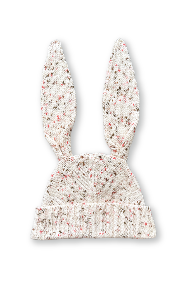 The GROWN Funfetti Bunny Beanie Pokie is a jersey knitted hat made from organic cotton, featuring long bunny ears on top and a cream-colored base with multicolored speckles.