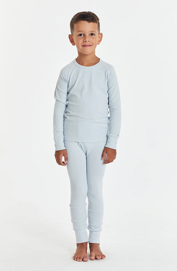 Boy wearing sleep set in arctic blue standing against white background