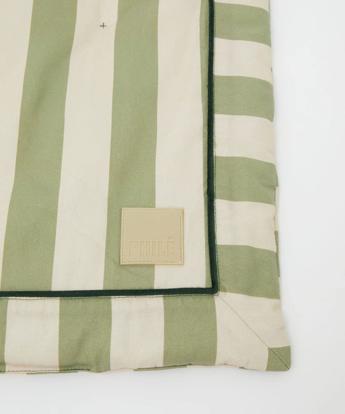 A close-up of the Philé - Striped Play Mat Green by PHILÉ, made from OEKO-TEX cotton with wide green and beige stripes and a beige "PHILÉ" patch, shown on a white background.