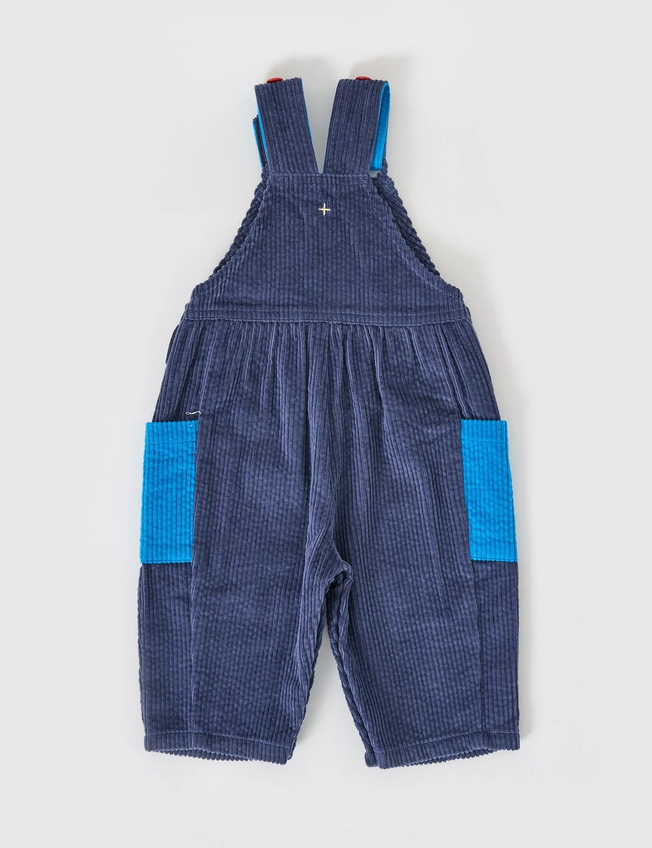The GOLDIE + ACE Goldie + Ace - Sammy Corduroy Colour Block Overalls for kids feature adjustable shoulder straps, wide legs, and oversized bright blue side pockets, shown laid flat on a light gray background.