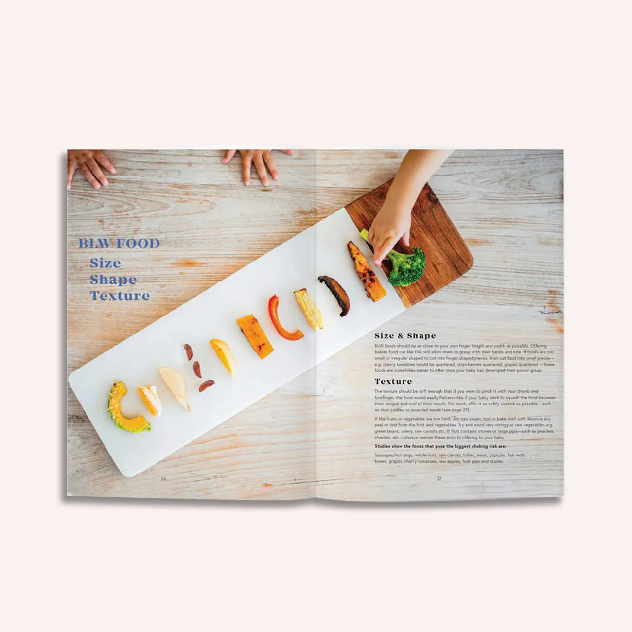 A magazine spread shows hands reaching for a long white platter of colorful foods arranged by size and shape on wood. Blue text reads, "BLW FOOD Size Shape Texture," featuring baby nutrition from Milk to Meals by Boob to Food's Luka McCabe.