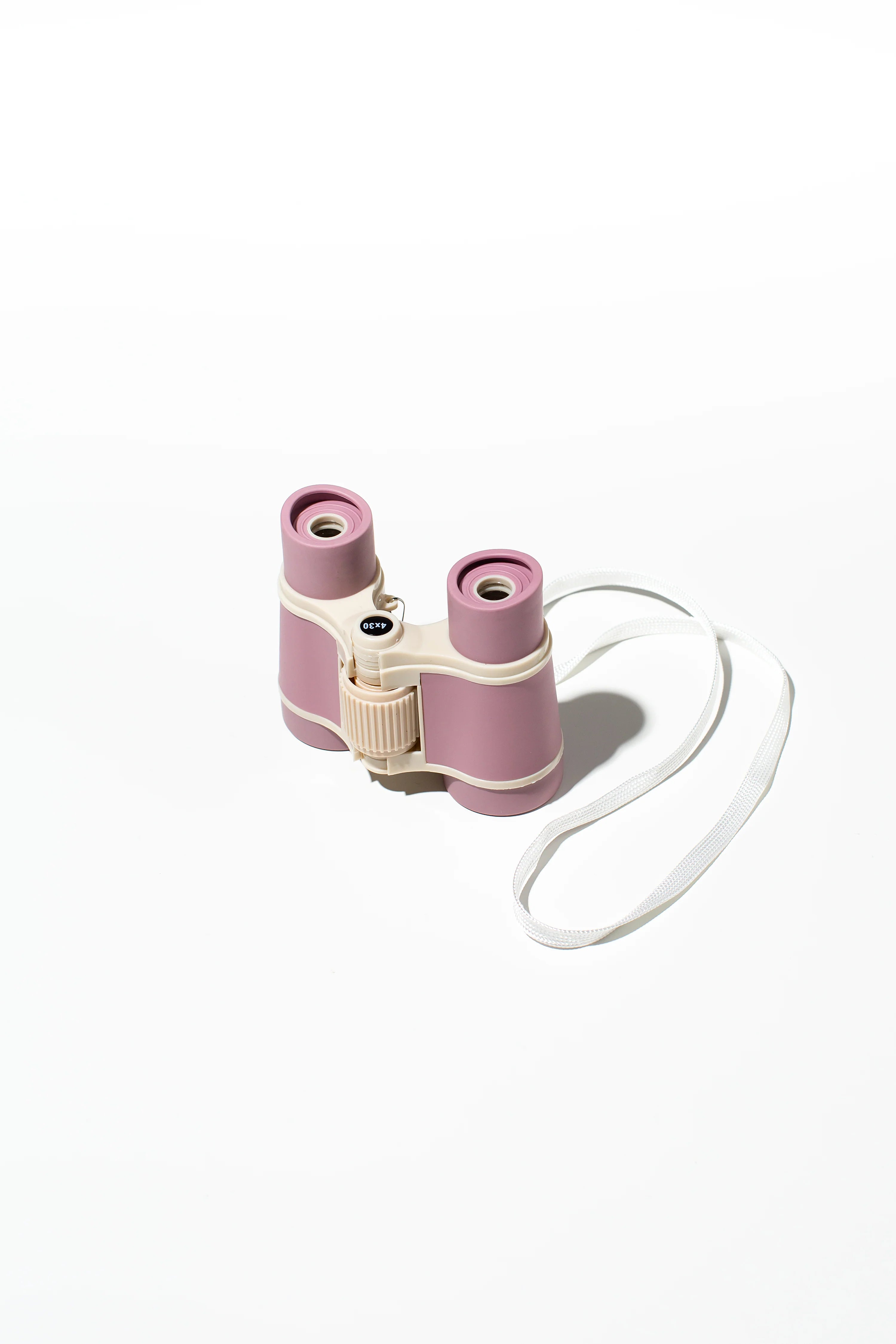 A pair of rose-colored Kids Explore Binoculars from LITTLE DROP, featuring a compact design, 4x30 zoom, and a ridged central focus wheel, with a white neck strap. Placed against a plain white background, these binoculars are perfect for your next scavenger hunt adventure!
