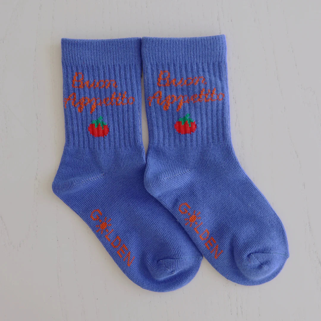 A pair of Buon Appetito Socks Pool Blue by GOLDEN CHILDREN, featuring "Buon Appetito" and a red tomato on the ribbed cuffs and "GOLDEN" in orange on reinforced toe caps, displayed on a white surface.