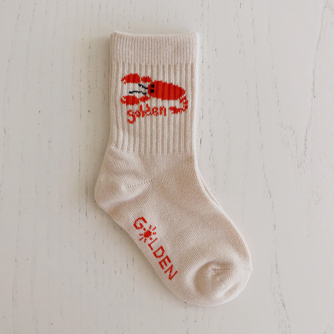 The GOLDEN CHILDREN Lobster Socks Tan are cream ribbed children's socks featuring a red crab and "Splash" above the ankle, with "GOLDEN" in red on the foot—ideal for fans of playful lobster designs.