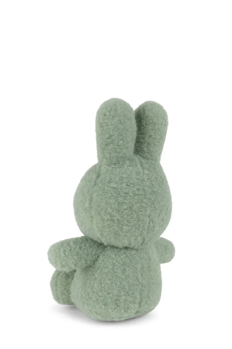 The Miffy ECO Cotton Candy Pistache 23cm by BON TON TOYS X MIFFY is a small, rabbit-shaped green plush toy with round ears and a simple design, made from recycled polyester. It sits with its back facing you against a white background.