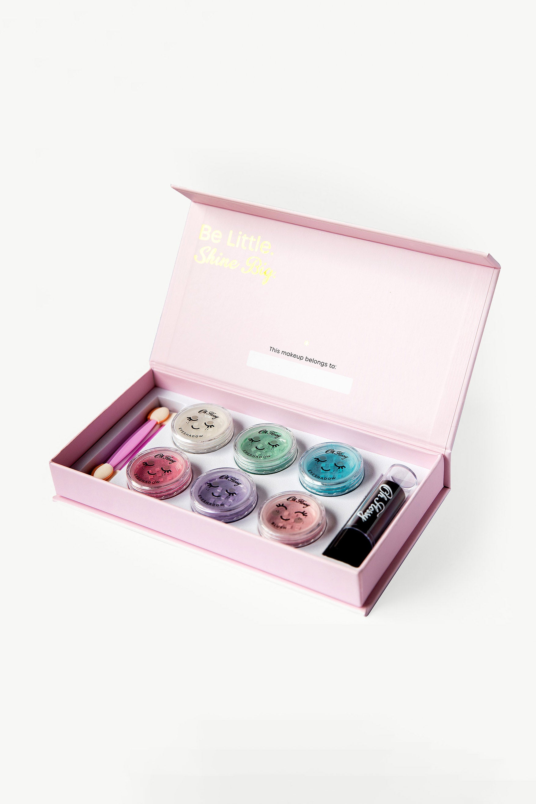 Open the OH FLOSSY ~ Deluxe Makeup Set to reveal a pink box containing six pastel eyeshadow pots with smiley faces, a dual-ended applicator, and a lipstick. The lid says "Be Little Shine Sky." Safe and non-toxic for kids, items rest neatly on a light background.