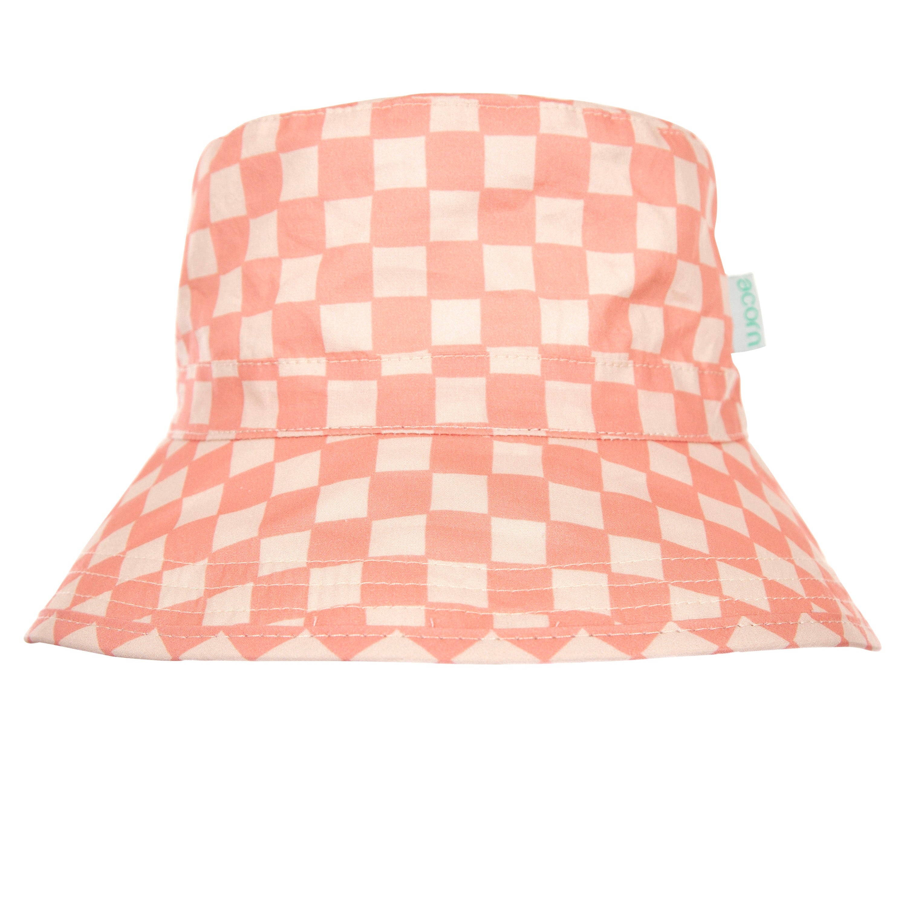 The Pink Checks Broad Brim Bucket Hat by ACORN KIDS combines a pink and white checkered cotton pattern with evenly spaced squares for a playful, stylish appearance. It features a small green tag on the side and offers excellent sun protection with its wide brim and round, soft top.