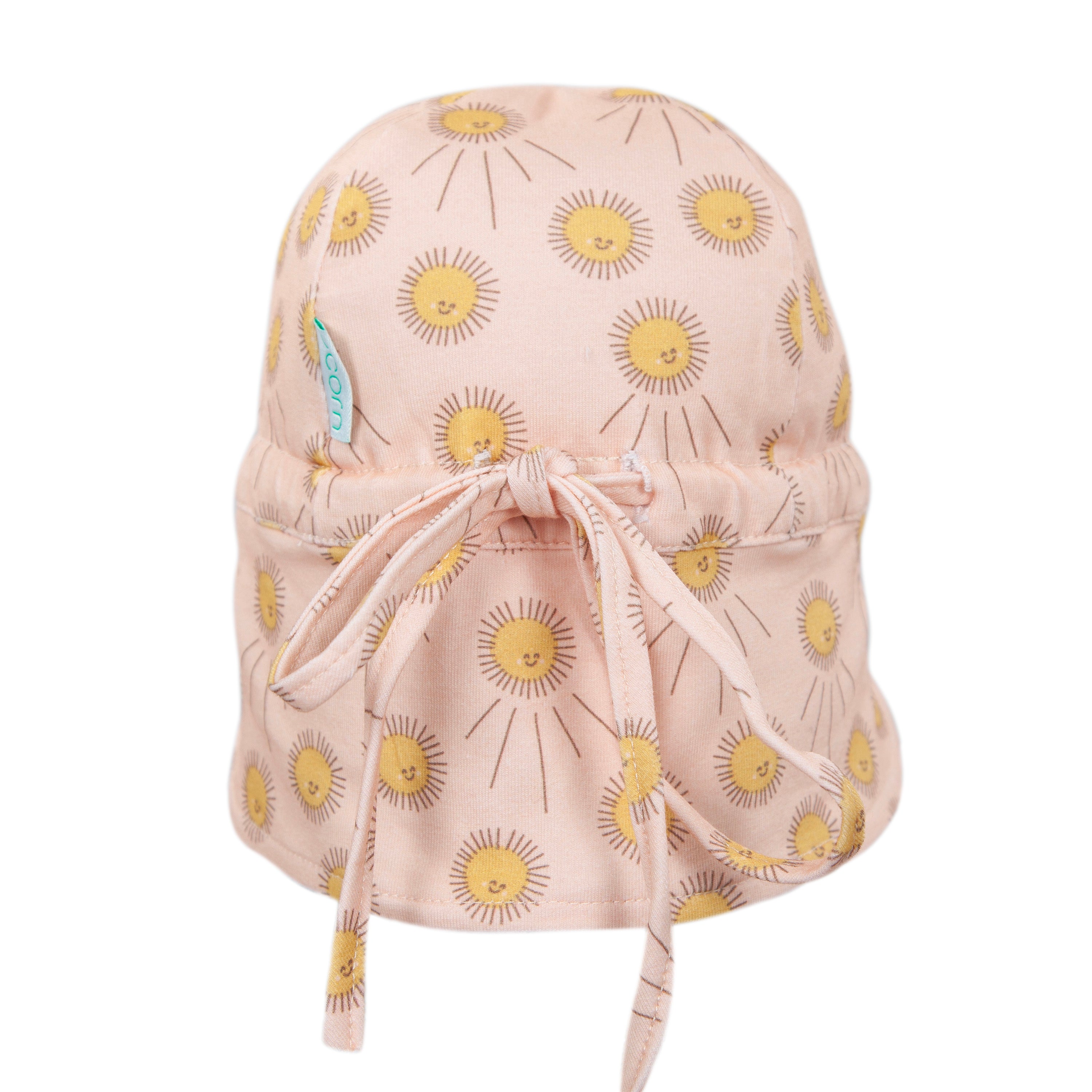 The Acorn Kids - Sunshine Flap Hat by ACORN KIDS is a light pink cotton jersey cap with smiling yellow sun prints, a back fabric tie, and UPF50+ sun protection.
