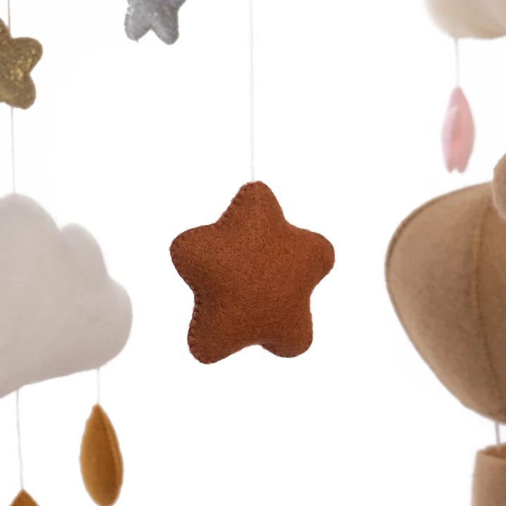 The ROOMI & ME Baby Mobile Sparkly Galaxy features a soft brown felt star and other felt shapes, like clouds and raindrops, all suspended on strings for gentle visual stimulation—perfect for your nursery.