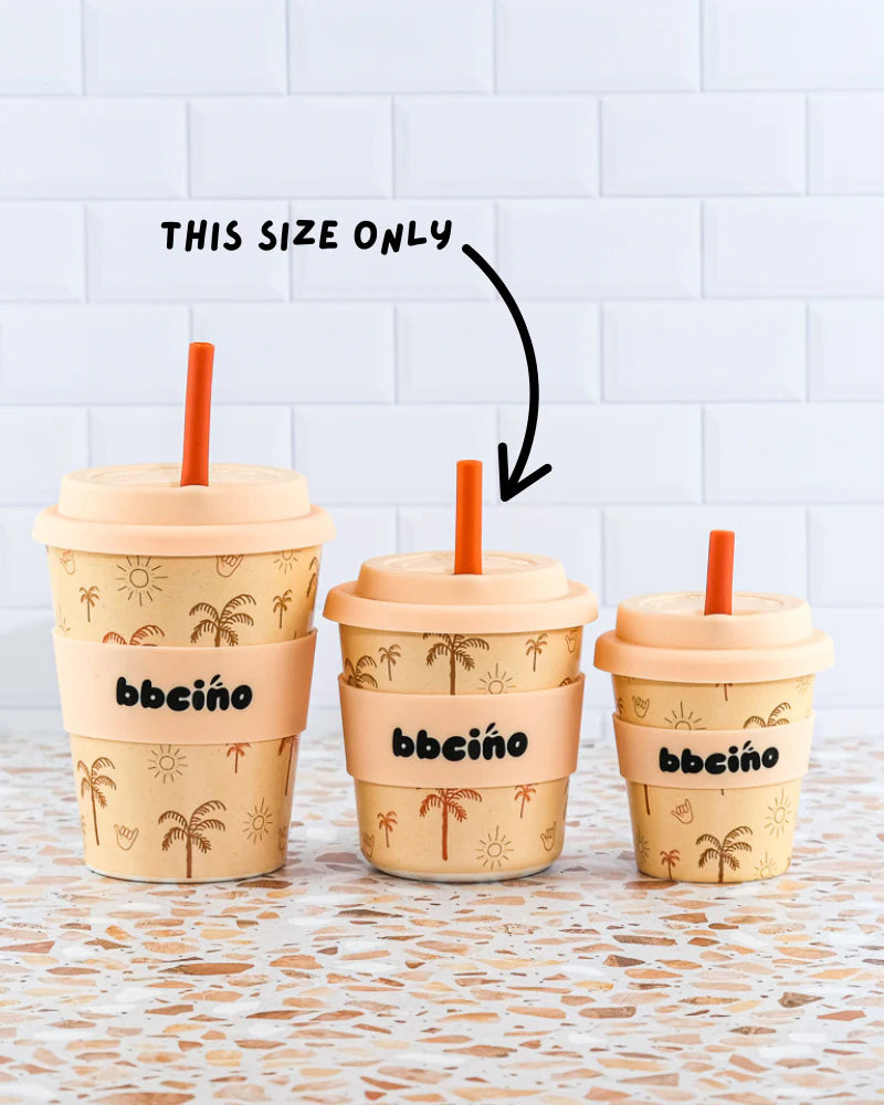 Three BBCINO BBcino Reusable BambinoCino Cups 240ml Oasis, made from sustainably farmed bamboo with a palm tree and sun design, sit on a countertop. An arrow marks the largest cup with “THIS SIZE ONLY.