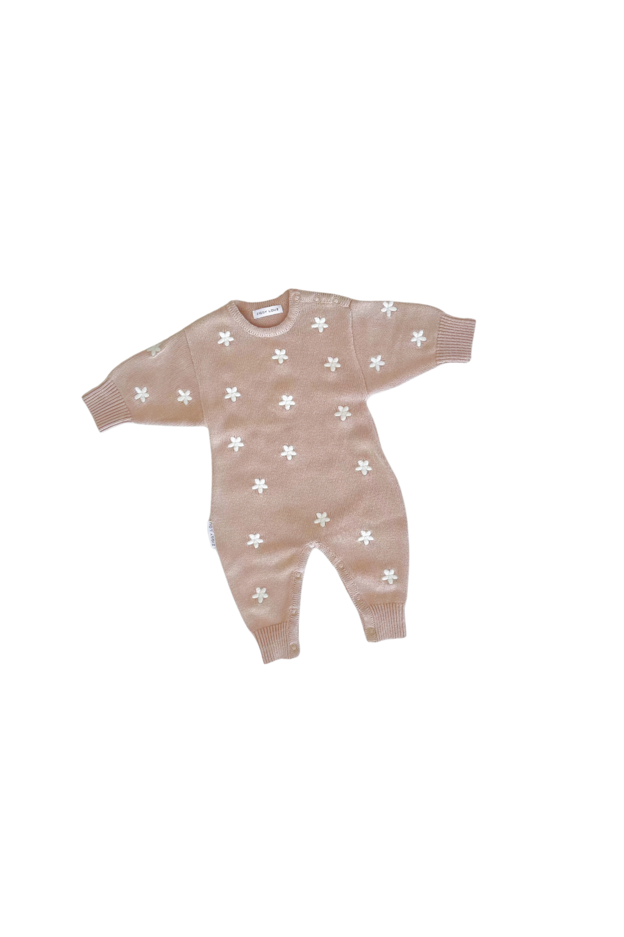 The ZIGGY LOU Winter Playsuit Aurora (Size NB), a light brown organic cotton knit with long sleeves, legs, and white flower patterns, is laid flat on a plain black background.