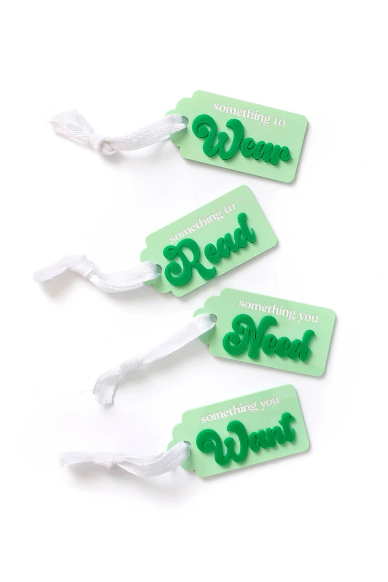 The WEAR, WANT, NEED, READ Tags Greens from HELLO KIT CO offer a personalized gifting experience with three green acrylic gift tags adorned with white ribbons. Each tag is uniquely labeled: "something to Wear," "something to Read," "something you Need," and "something you Want." This delightful tradition adds a personal touch to every gift.