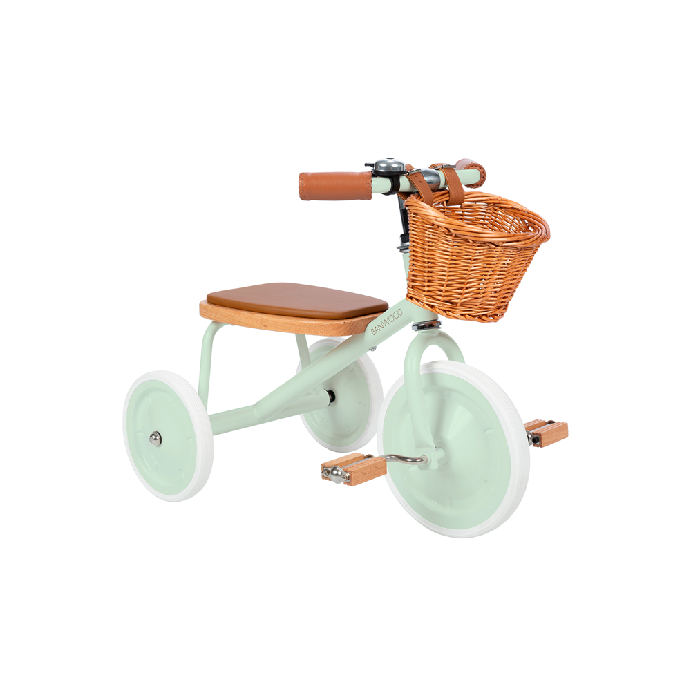 The Banwood - Trike Pale Mint is a vintage-style kids' tricycle from BANWOOD with a pastel green frame, brown seat, handle grips, white wheels, a wicker basket on the handlebars, and wooden pedals.