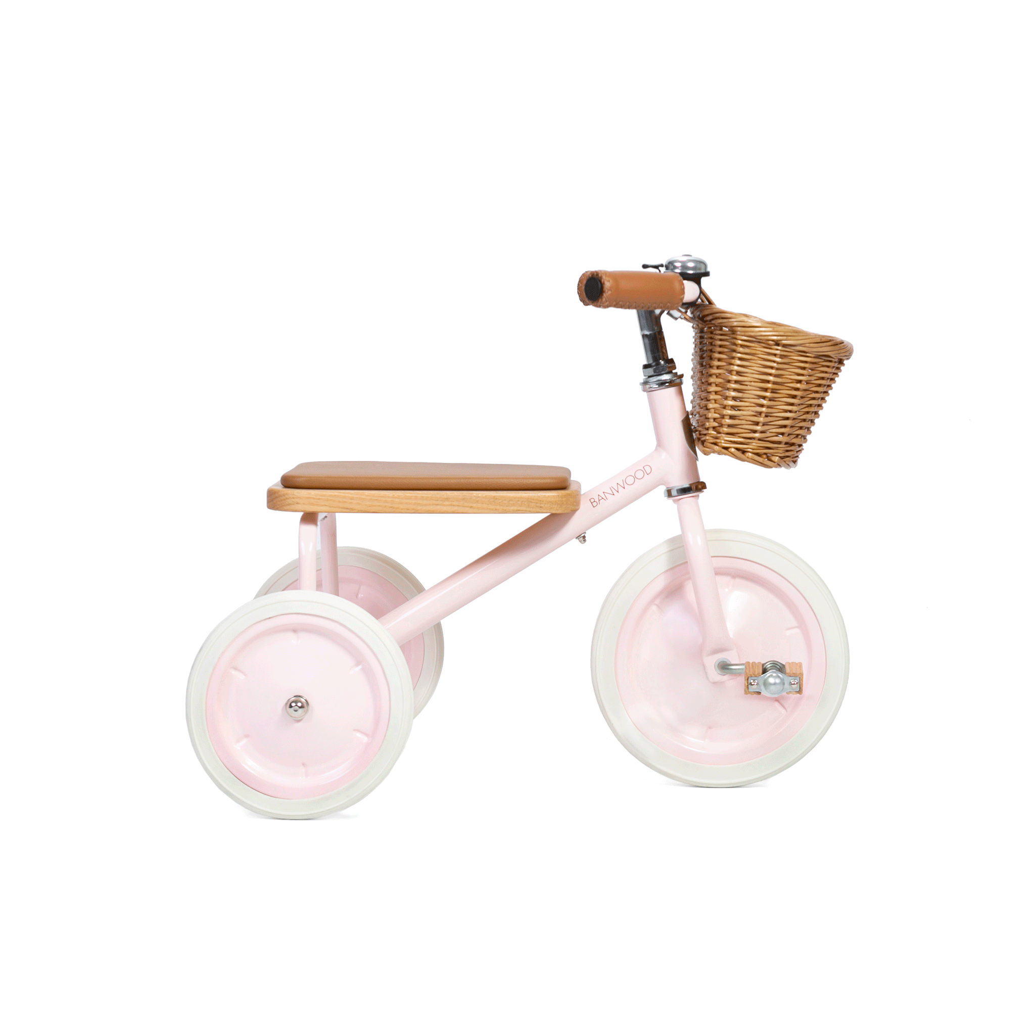 The Banwood - Trike Pink by BANWOOD is a charming tricycle for kids, featuring a pink frame, white tires, a wooden seat, brown handlebars, and a small wicker basket on the front, all set against a plain white background.