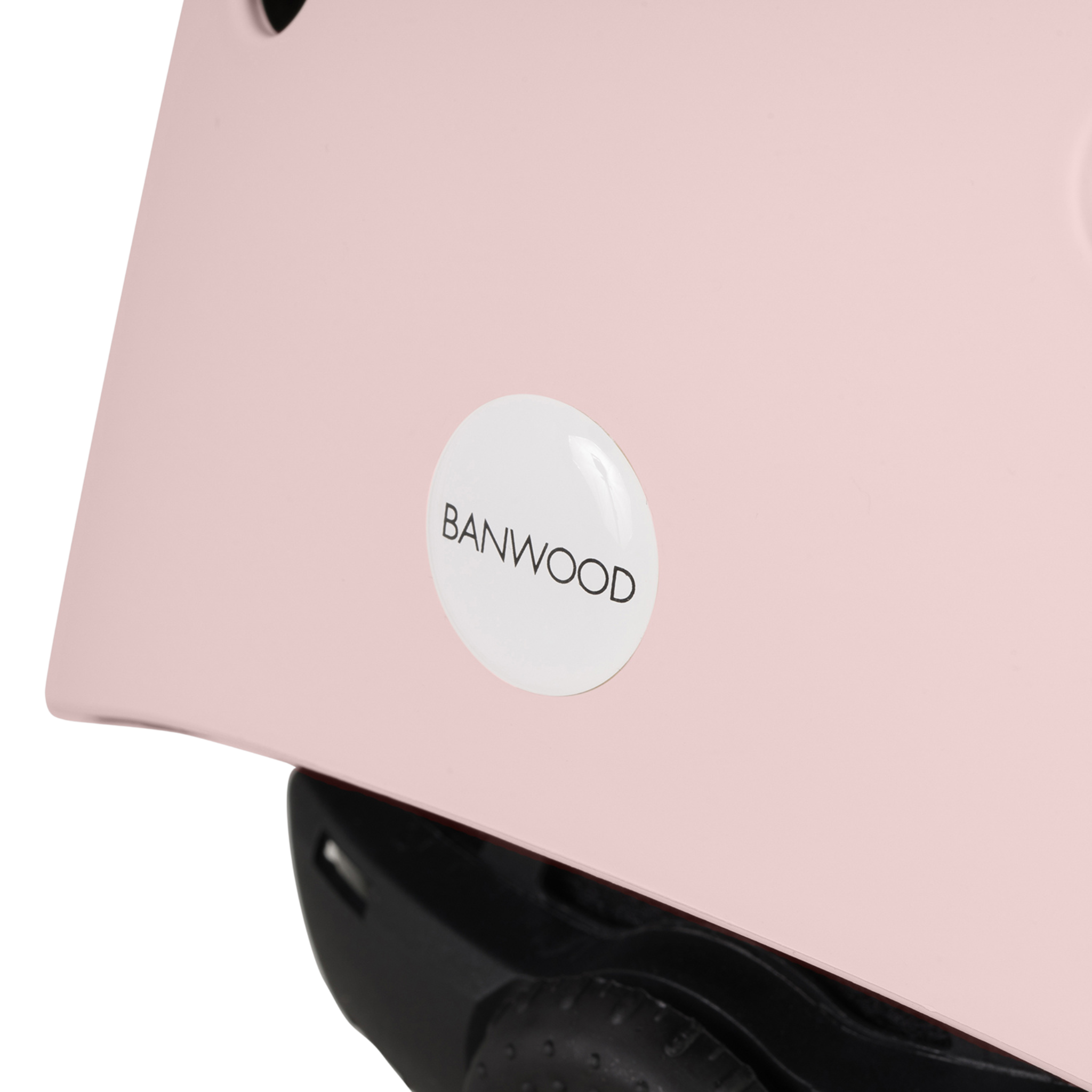 Close-up of the Banwood Eco Helmet Faded Pink, made from recycled ABS, with a round white logo featuring "BANWOOD" in black letters.