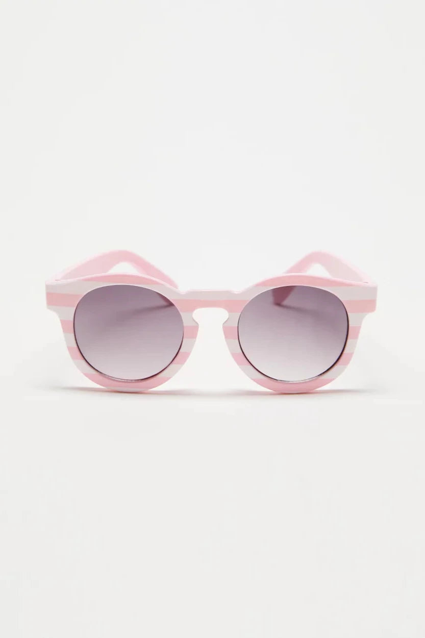 The Baby Pixie Sunglasses Pink Stripe by FRANKIE RAY feature round frames with pink and white stripes made from rubber, paired with tinted, impact-resistant lenses. Positioned against a plain background, these sunglasses offer a stylish and playful design while ensuring 100% ultraviolet protection.