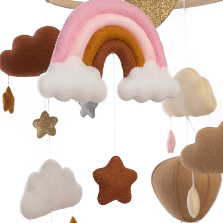 The ROOMI & ME Baby Mobile Sparkly Galaxy features soft, handmade rainbows, stars, and clouds in pink, brown, gold, and beige—perfect for gentle visual stimulation in any nursery.