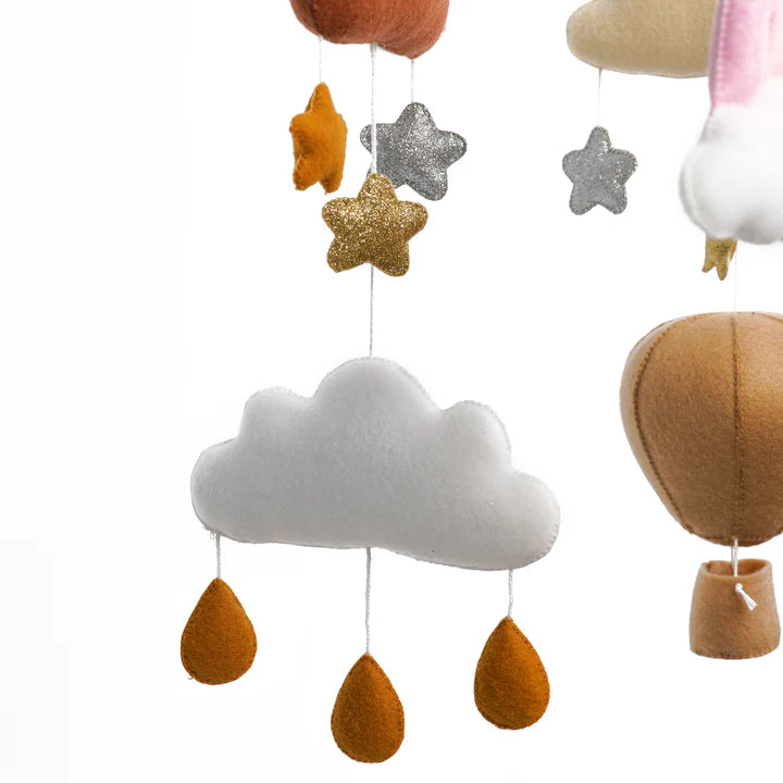 The ROOMI & ME Roomi & Me - Baby Mobile Sparkly Galaxy features a handmade white felt cloud, orange raindrops, glittery gold and silver stars, and tan hot air balloons for gentle visual stimulation against a white backdrop.
