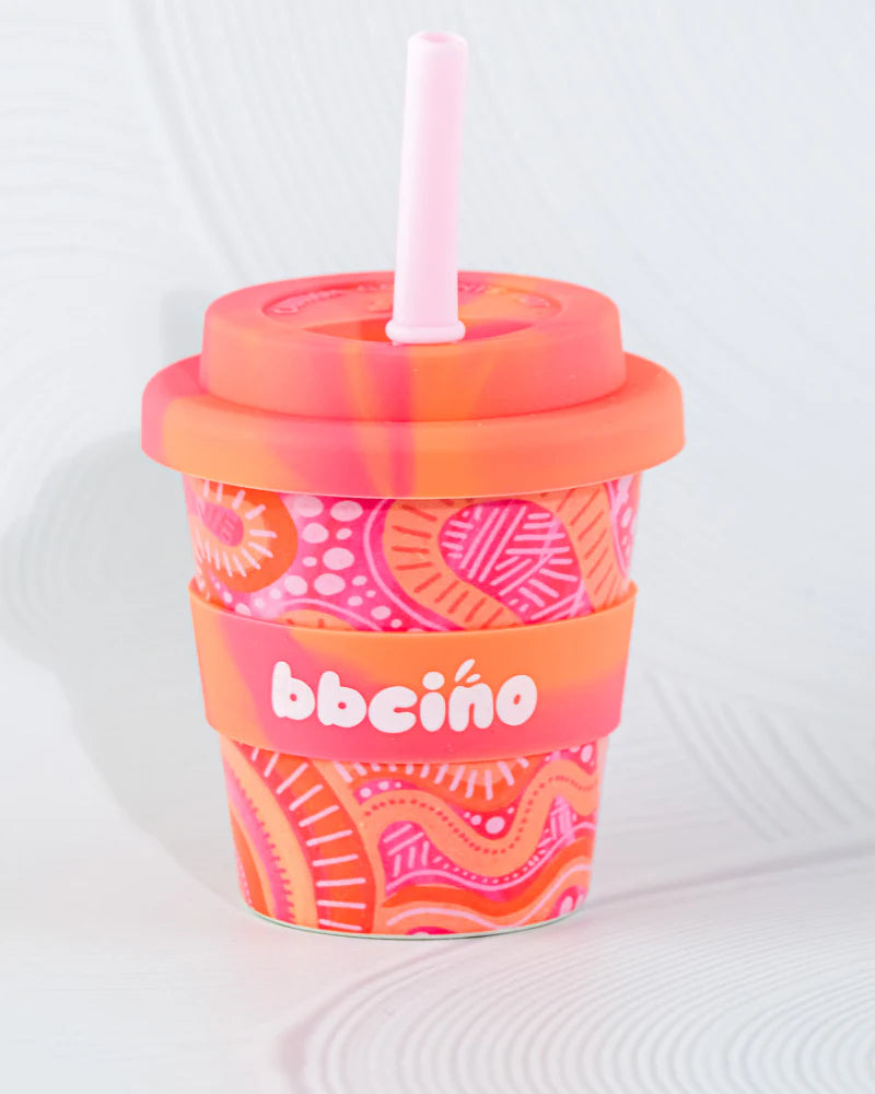 The BBcino Reusable Babycino Cup 120ml Mum and Bub features sustainably farmed bamboo, a pink and orange lid, straw, and sleeve with vibrant paisley patterns. The sleeve shows the "BBCINO" brand name in white.