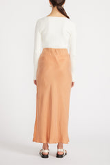 Rear view of woman in white top and Elsie Cupro Skirt in Ginger.