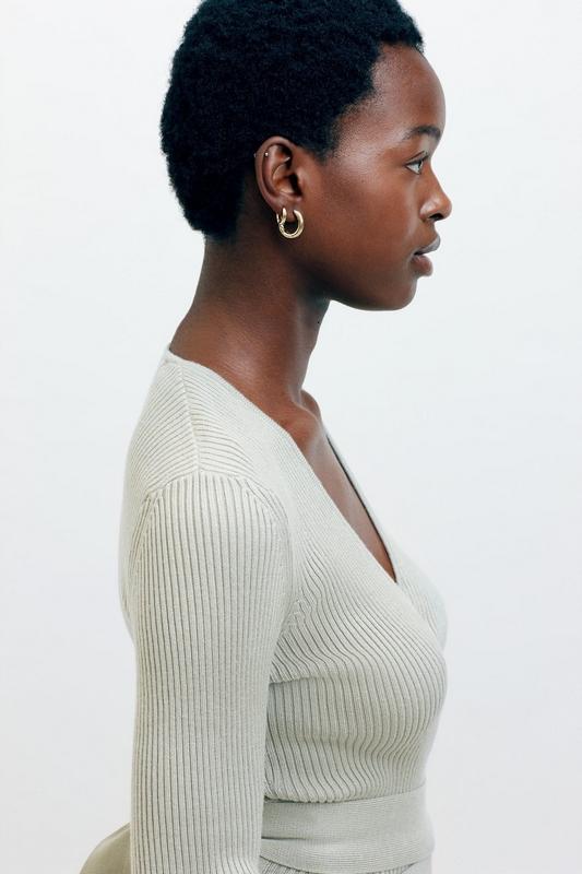 Woman standing side on wearing gold hoop earrings