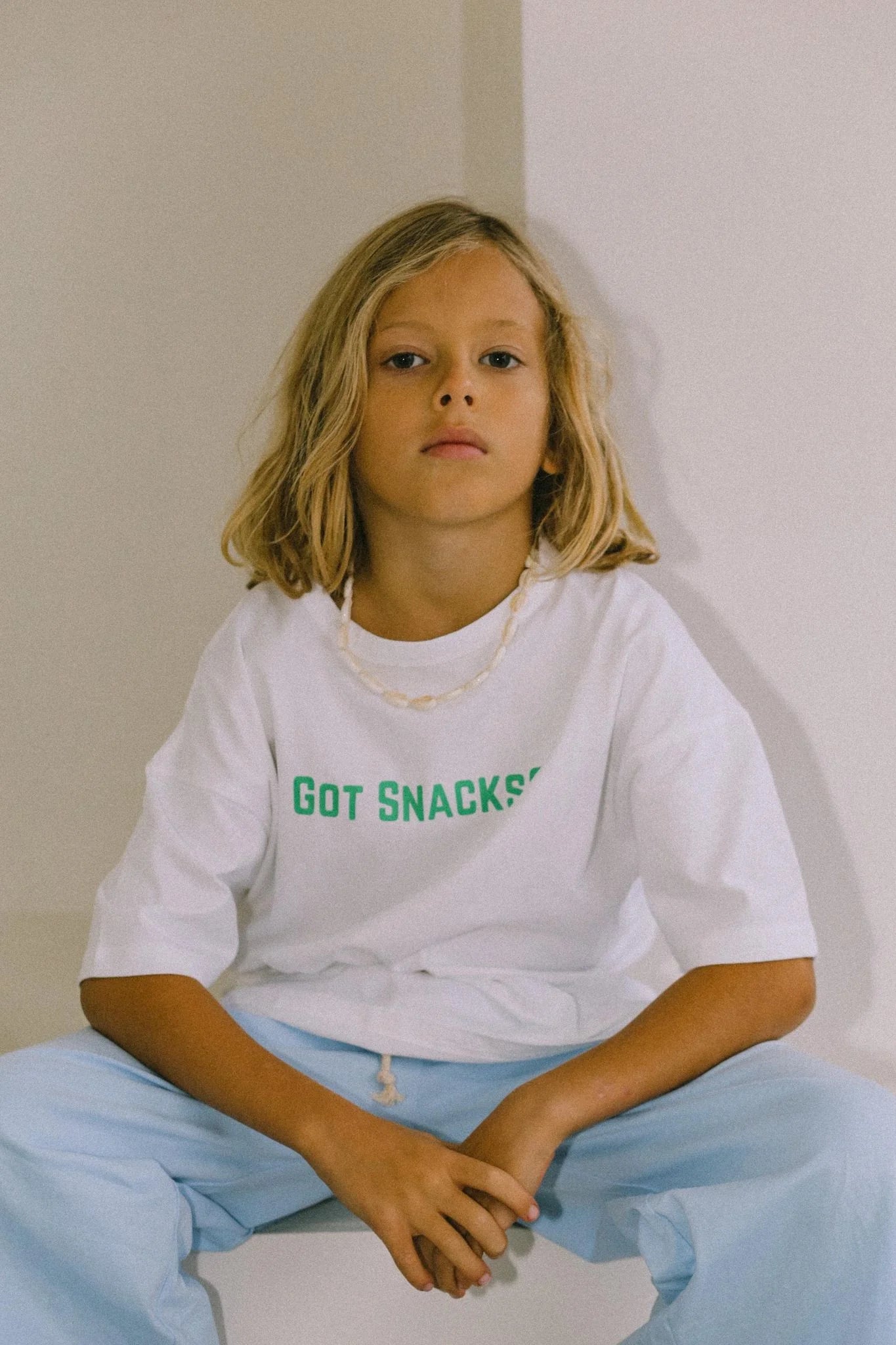 Young boy sitting down wearing got snacks tee.