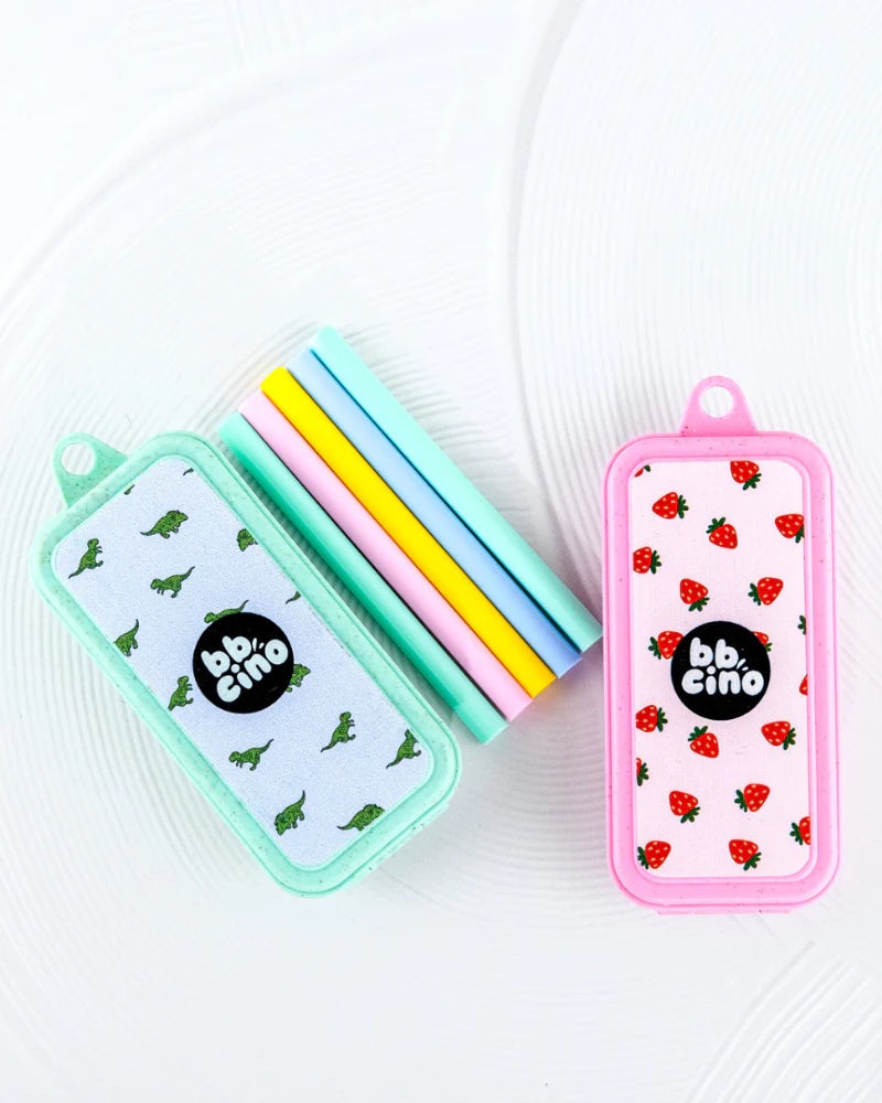 A Replacement Silicone Straw Set Berry OR Dino from BBCINO is displayed with two rectangular cases—one in teal featuring dinosaurs and the other in pink adorned with strawberries. Accompanying them are four pastel-colored reusable silicone straws in blue, yellow, pink, and green. These eco-friendly straws are BPA-free, and each case showcases the BBCINO brand logo prominently in the center.